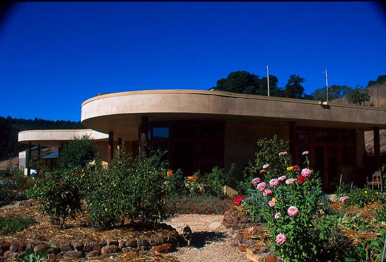 A retaining wall forms the back of the living quarters, which helps keep the home cool and allows the structure to nestle into the hillside. The home’s 96 solar panels are placed on the roof of the garage/workshop and above the covered walkway.